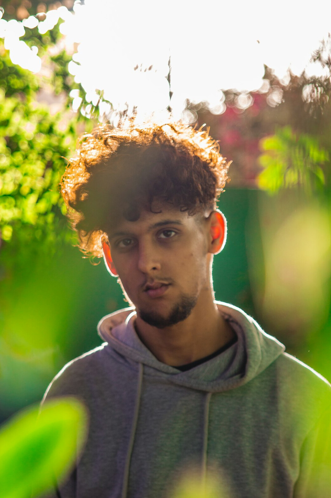 Studio portrait of a slovenian man in his 20s with curly hair wearing a hoodie